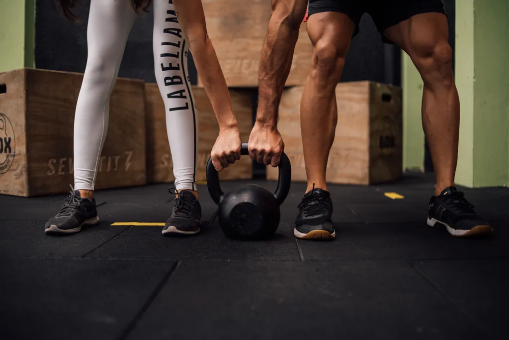 Trener dodaje kettlebell klijentu u teretani
